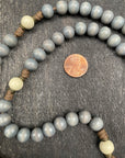 Close-up of a lightweight rosary with small, smooth beads and a detailed coin pendant, emphasizing the contrast in textures between the beads and the coin, ideal for collectors and spiritual practices.