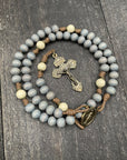 Lightweight rosary set against a soft, neutral background, showcasing smooth, polished beads, a streamlined metallic crucifix, and a subtle oval center medal, perfect for travel, daily prayer, or as a meaningful gift.