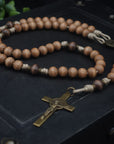 paracord rosary with tan and gray-brown wooden beads and bronze St. Benedict crucifix resting on black box