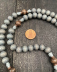 A rosary necklace featuring a penny, elegantly displayed on a rustic wooden table.