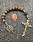 Close-up of a rosary with sand-colored beads, durable knots, a detailed copper-colored crucifix, and a beautiful pendant, displayed on a light wooden surface with a penny for size comparison, ideal for prayer and reflection.