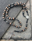 Handmade rosary with gray-brown and charcoal wood beads, silver St. Benedict crucifix, and black paracord