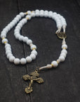Handcrafted rosary featuring white wood beads, bronze crucifix, and gold spacer accents on cream paracord for weddings and first communion gifts