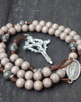 Close-up of silver Crown of Thorns and Nails crucifix on Holy Sepulcher rosary with dark wood beads