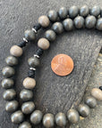 Detailed view of stained gray and charcoal wood beads with natural variations on black paracord rosary
