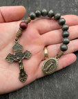 Full view of a rosary with a detailed metallic crucifix and beautiful pendant, placed on a hand with a light gray table, ideal for prayer and spiritual reflection.