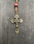 Close-up of a detailed metallic rosary crucifix with dark wooden beads and durable knots, placed on a light wooden table, ideal for prayer and reflection.