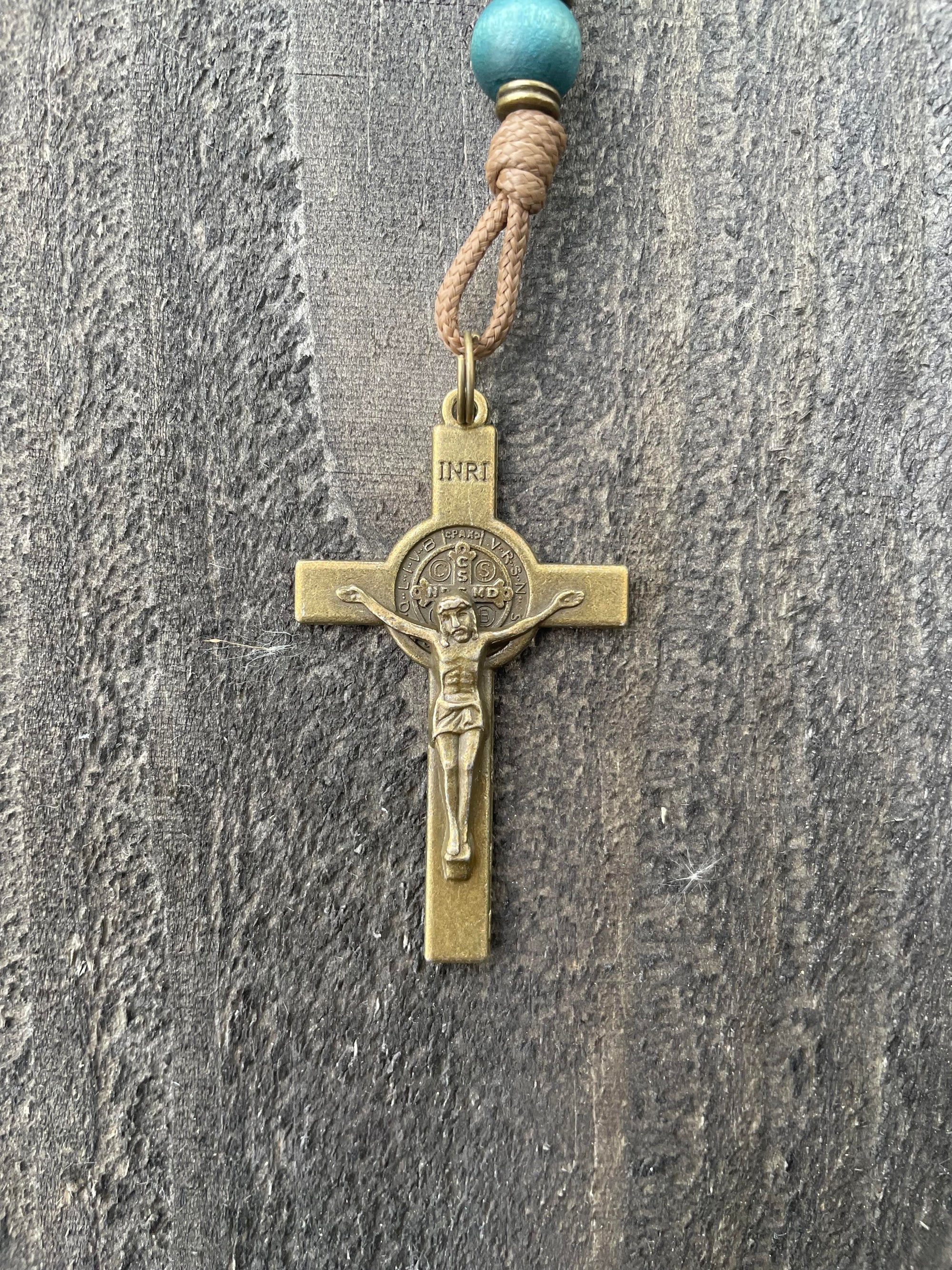 Close-up of bronze St. Benedict crucifix on Noel Christmas rosary with teal and gray beads
