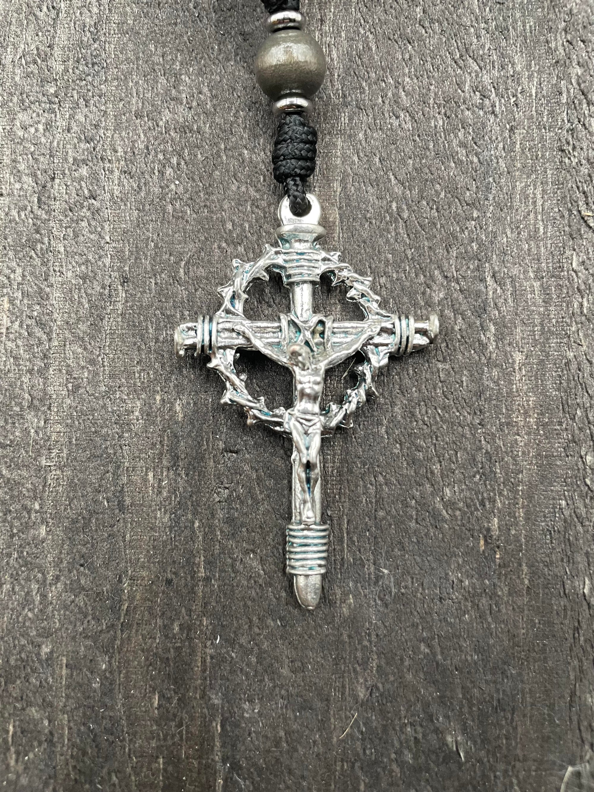 Close-up of a crucifix featuring a thorny crown, placed on a wooden gray table, symbolizing faith and spiritual devotion.