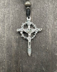 Close-up of a crucifix featuring a thorny crown, placed on a wooden gray table, symbolizing faith and spiritual devotion.