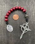 Close-up of a rosary with deep red beads, red knot accents, and an intricately designed crucifix pendant, ideal for prayer and spiritual reflection.