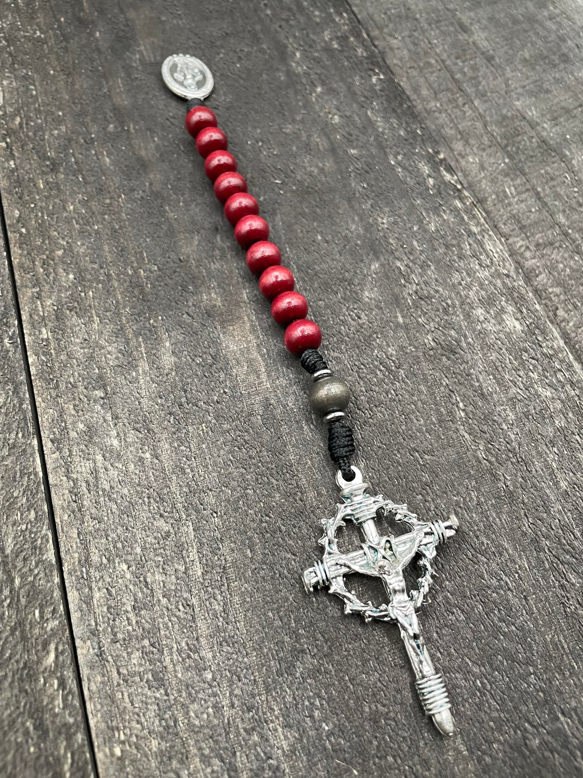 Close-up of a rosary with rich red beads, red knot accents, and a detailed crucifix pendant, designed for prayer and spiritual devotion.
