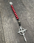 Close-up of a rosary with rich red beads, red knot accents, and a detailed crucifix pendant, designed for prayer and spiritual devotion.