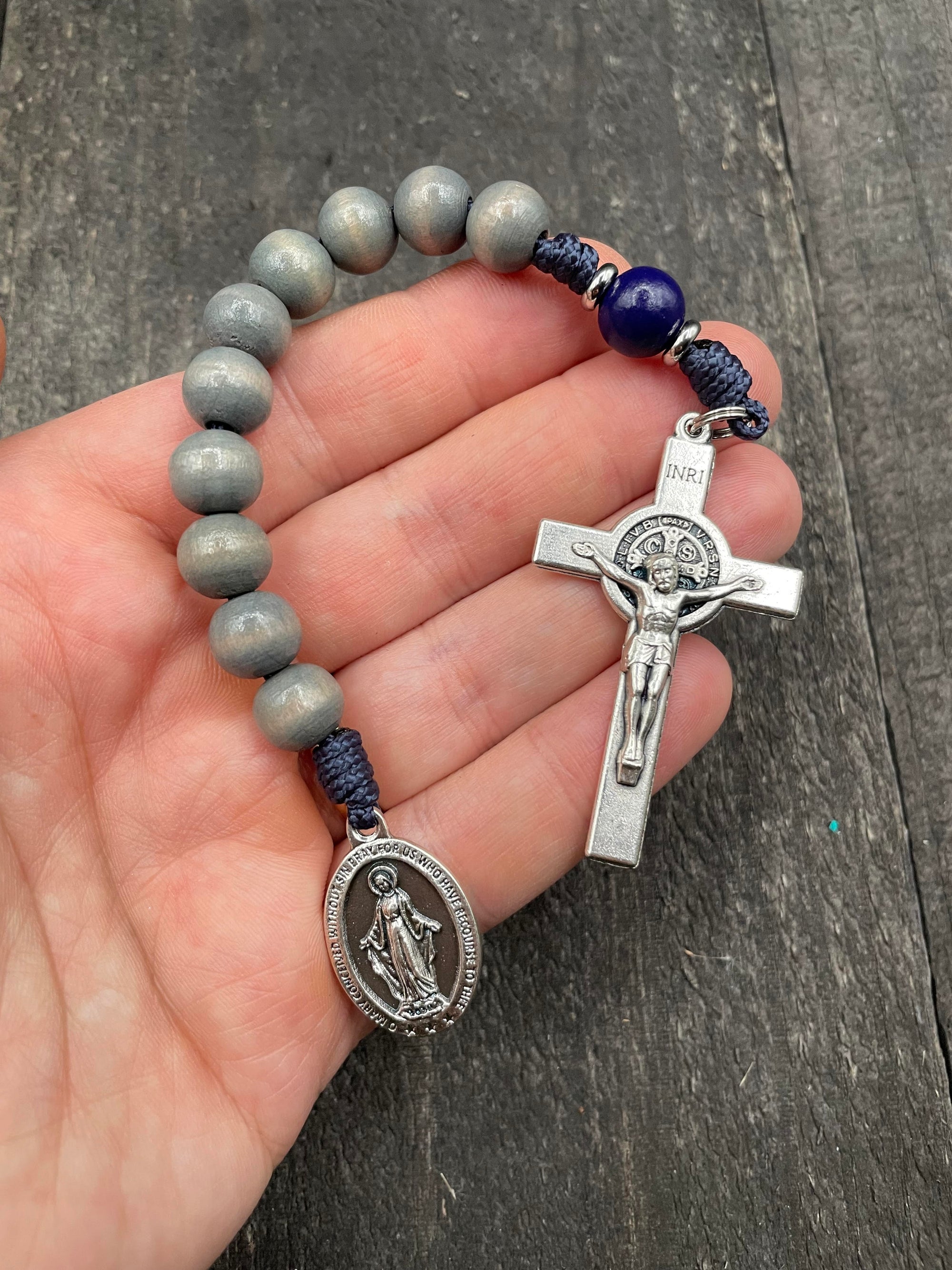 Full view of a rosary with blue beads, durable knots, and a detailed silver crucifix featuring a Marian pendant, displayed on a hand, ideal for prayer and devotion.