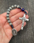 Full view of a rosary with blue beads, durable knots, and a detailed silver crucifix featuring a Marian pendant, displayed on a hand, ideal for prayer and devotion.