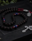St. Carlo Acutis rosary with walnut and royal blue wooden beads, silver Pardon crucifix, and durable burgundy paracord
