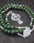 Close-up of silver Celtic crucifix on St. Dymphna rosary with forest green wooden beads