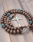 Close-up of silver Nails crucifix on St. Kateri rosary with gray-brown and teal wood beads
