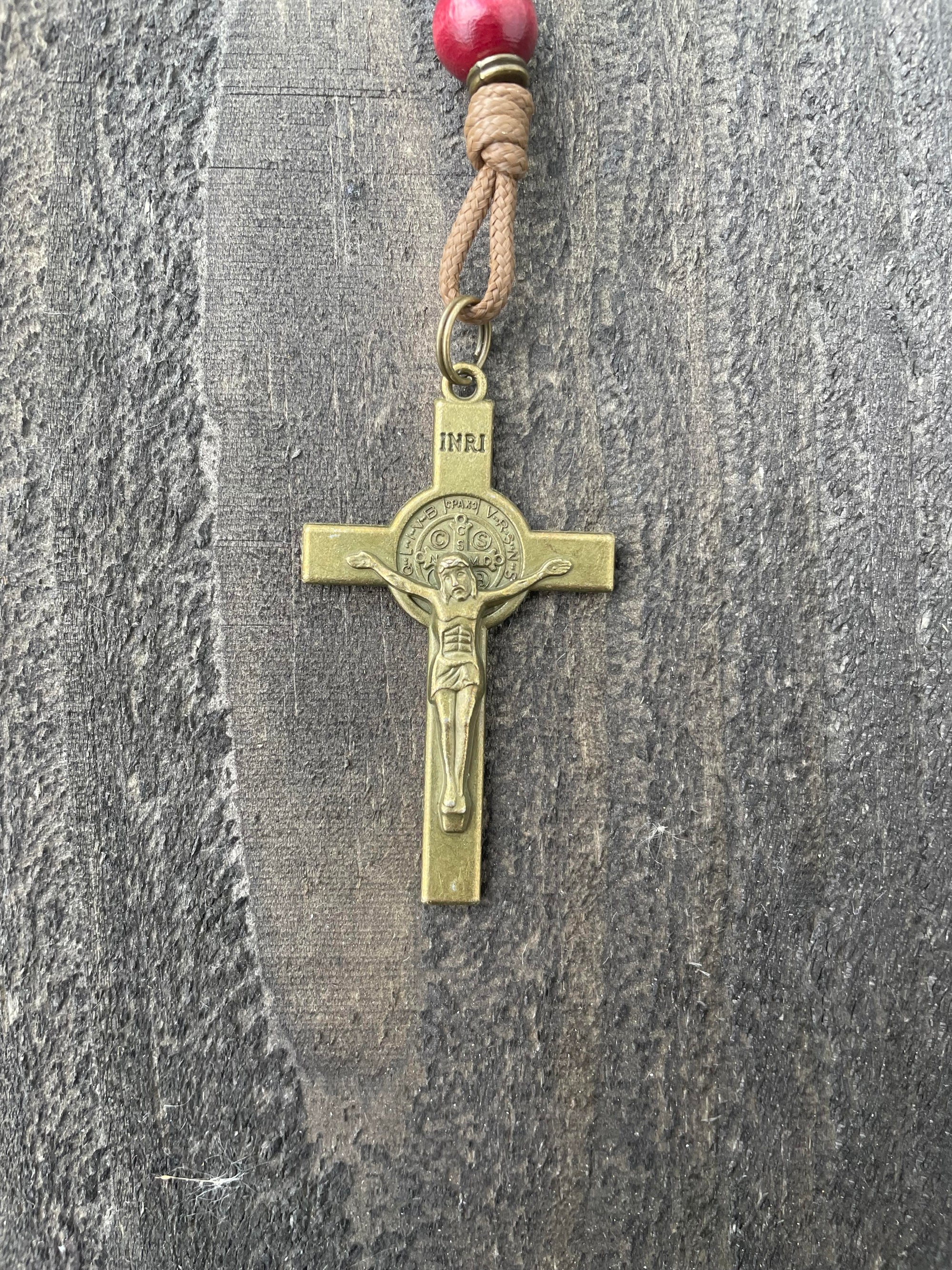 Close-up of bronze St. Benedict crucifix on St. Nicholas Christmas rosary with wood beads and paracord
