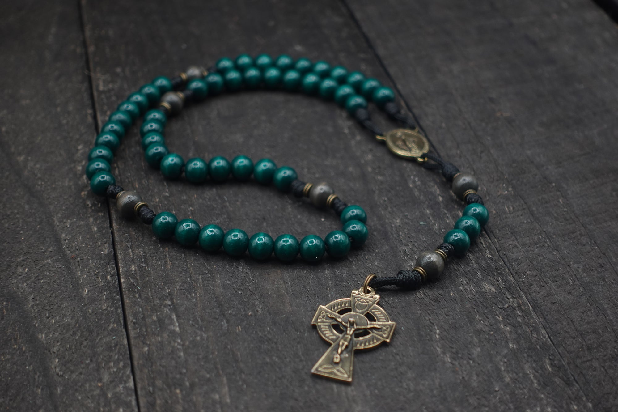 St. Patrick rosary with emerald green and charcoal wooden beads, bronze Celtic crucifix, and black paracord