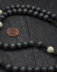 Close-up of bronze Pardon crucifix on Augustinian rosary with charcoal and white wooden beads