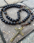 Black Benedictine rosary by Runewood Rosary combining black wood beads, bronze crucifix, and walnut paracord for faithful devotion