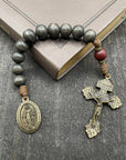 Close-up of a rosary with wooden beads, durable knots, and a detailed crucifix, lying on a book placed on a light wooden table, ideal for prayer and spiritual reflection.