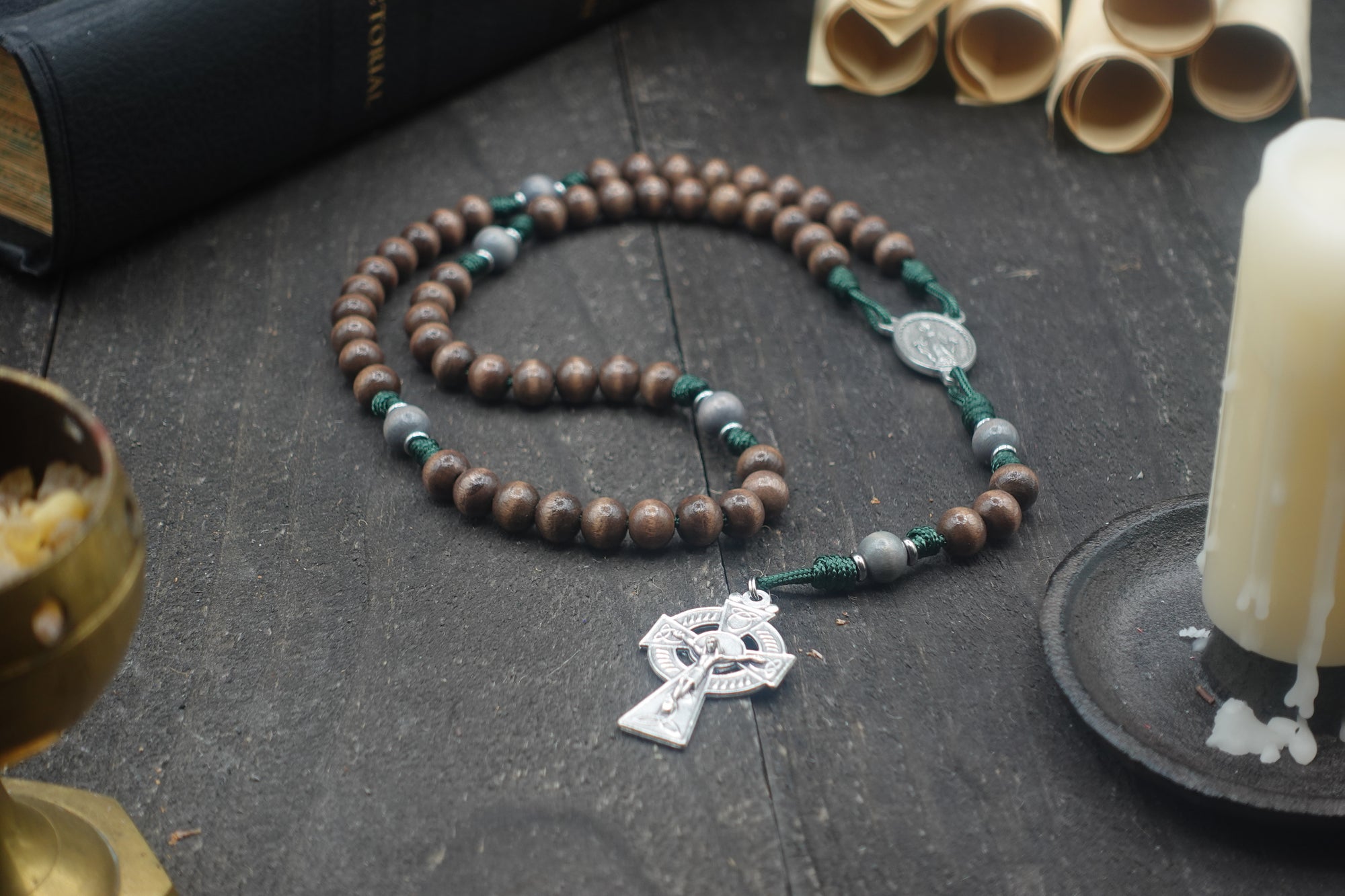 Handmade Celtic rosary featuring gray-brown wooden beads, silver crucifix, and emerald green paracord