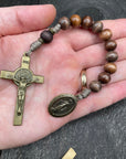 Full view of a rosary with sand-colored beads, durable knots, a detailed copper-colored crucifix, and a beautiful pendant, placed on a hand, ideal for prayer and spiritual devotion.