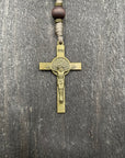Close-up of a detailed copper-colored crucifix with sand-colored beads and durable knots, displayed on a light wooden surface, ideal for prayer and reflection.