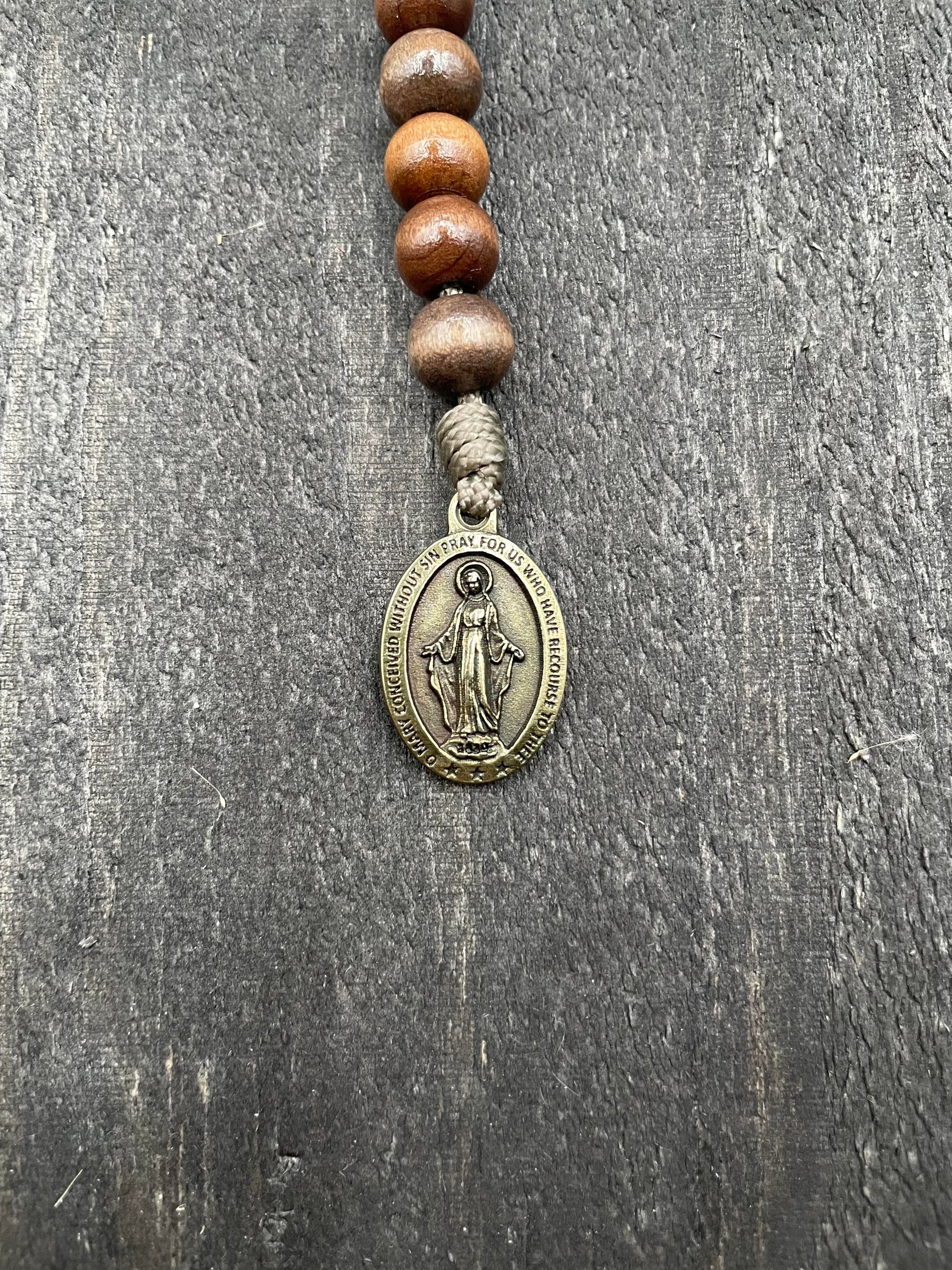 Handmade pocket paracord rosary featuring stained brown wood beads and bronze hardware