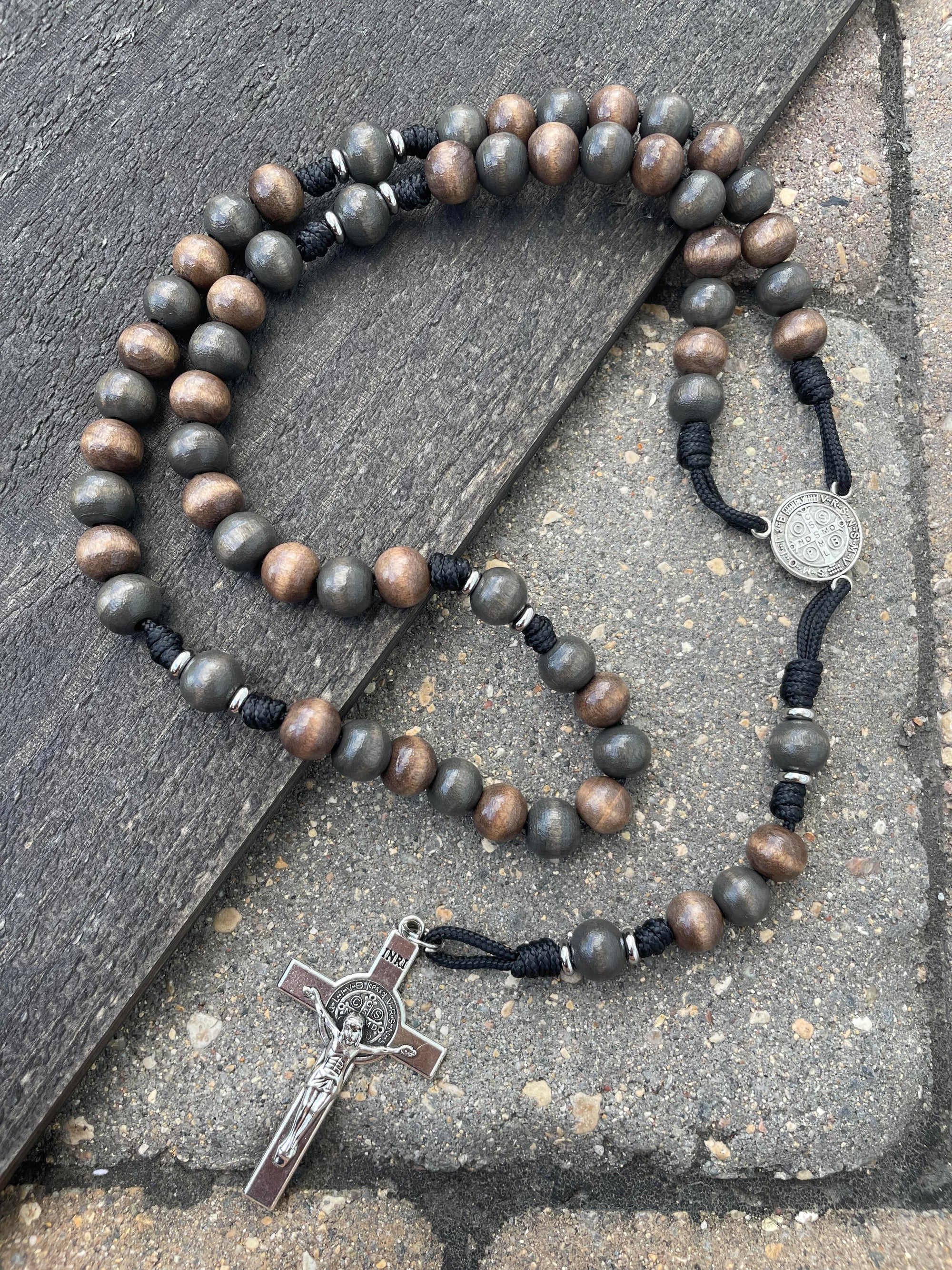Handmade rosary with gray-brown and charcoal wood beads, silver St. Benedict crucifix, and black paracord