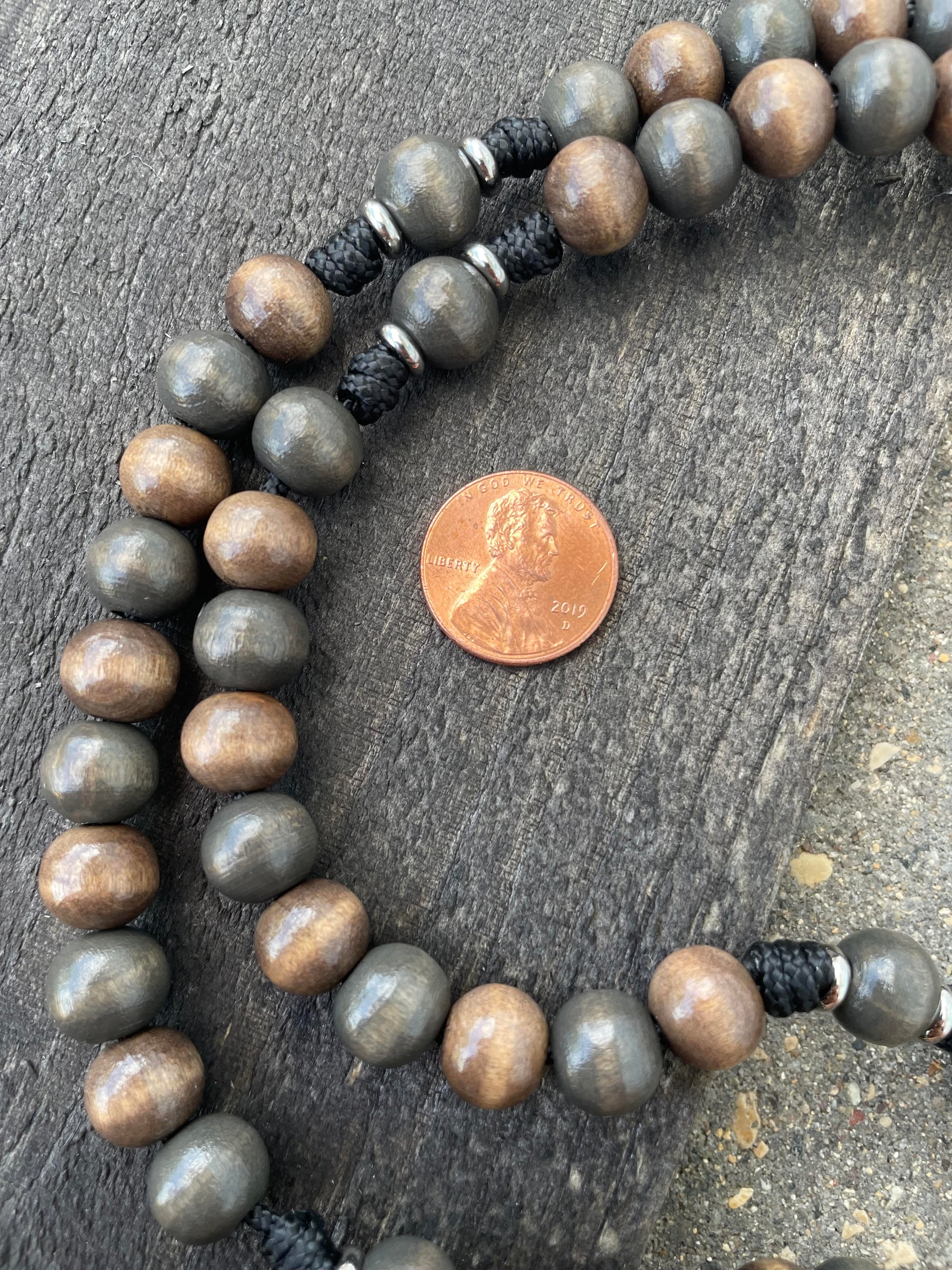 Detailed view of hand-stained wooden beads on black paracord rosary built for daily devotion