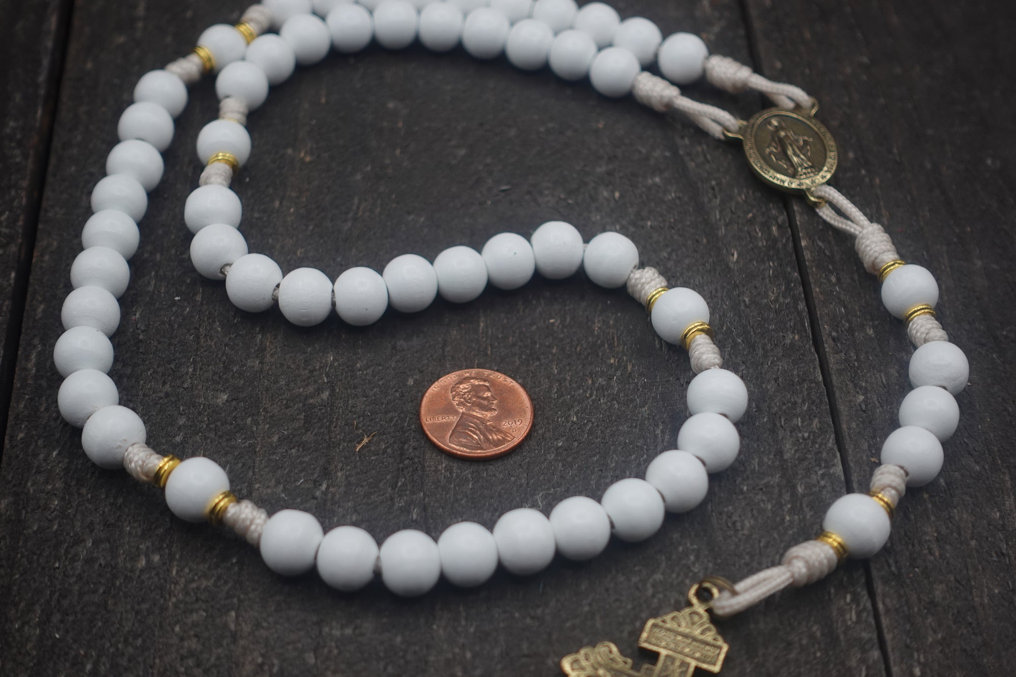 Close-up of white wooden beads and gold spacers on Heavenly Grace rosary showing heirloom craftsmanship