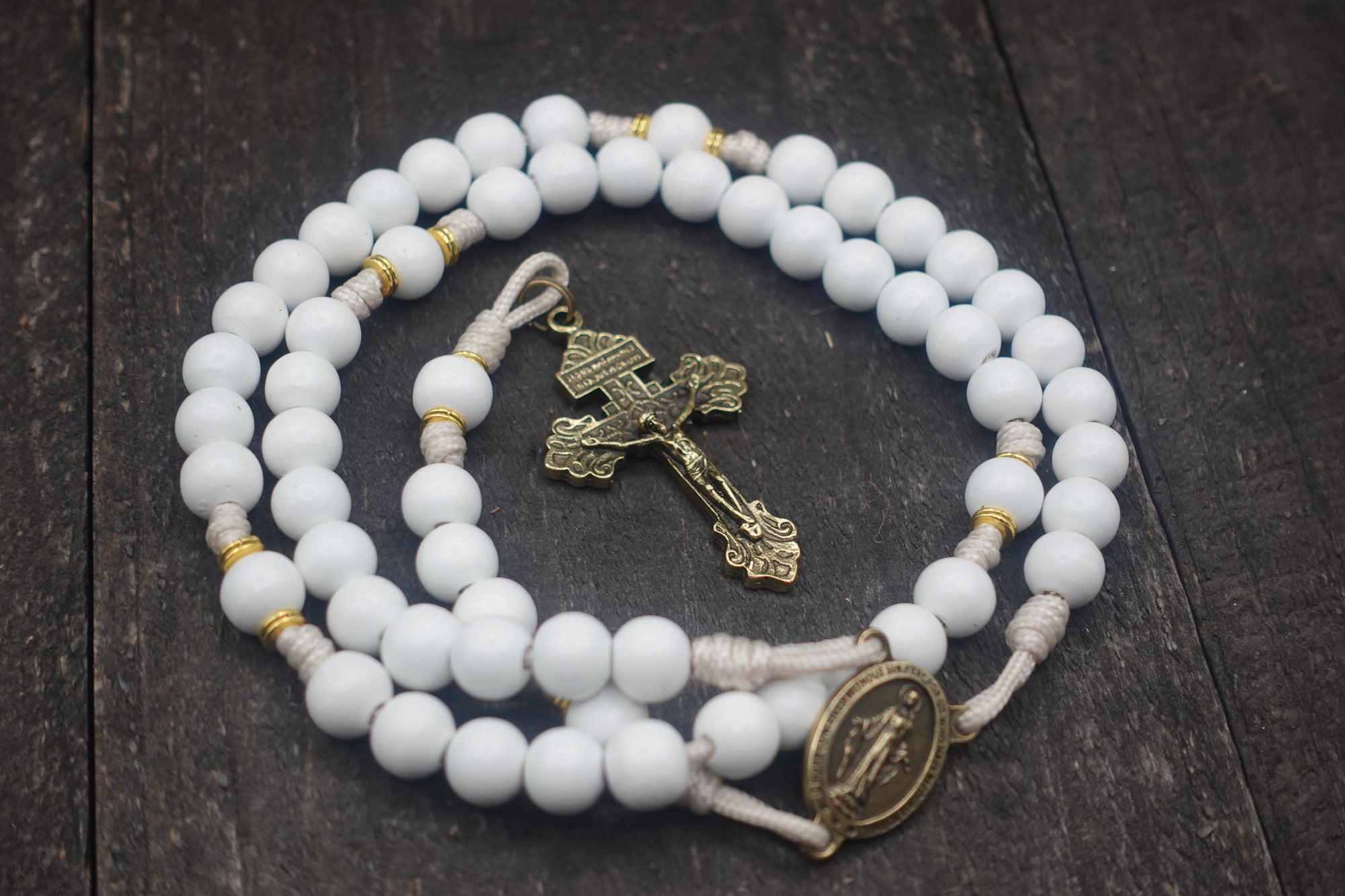 Heavenly Grace rosary for wedding and first communion gifts with white wooden beads, gold spacers, bronze Pardon crucifix, and cream paracord