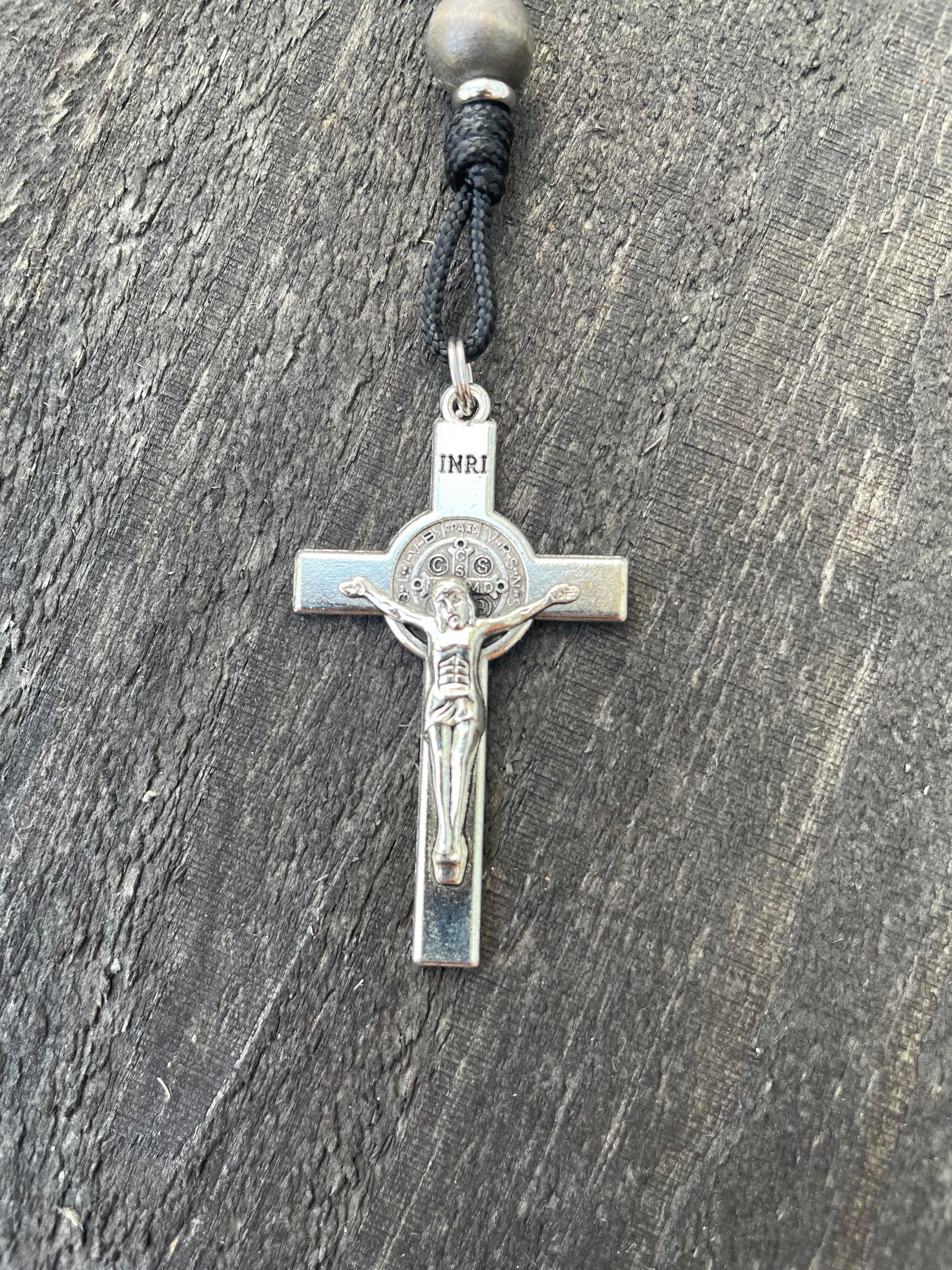 Close-up of silver St. Benedict crucifix on rosary with gray and charcoal wood beads