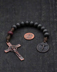 Handmade paracord rosary featuring charcoal wood beads and bronze Pardon Crucifix hardware