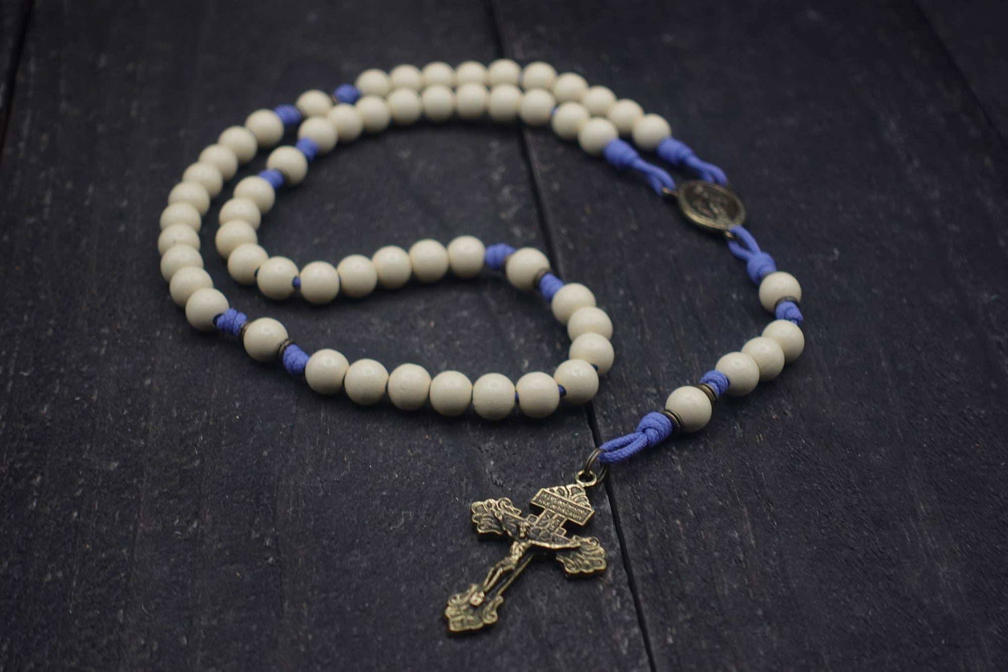 Handcrafted womens rosary featuring white wood beads, bronze crucifix, and spacer beads on lavender paracord