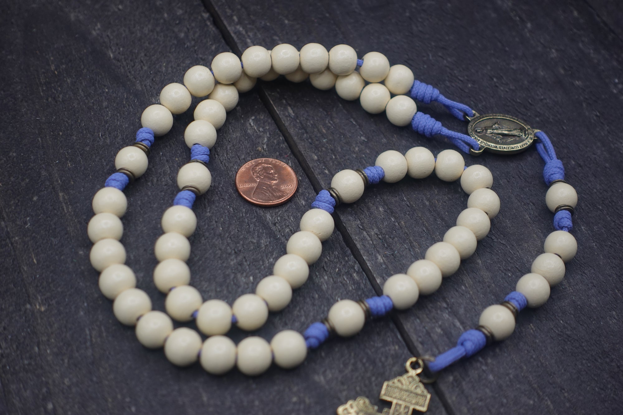 Detailed view of white wood beads with bronze accents on lavender paracord womens rosary