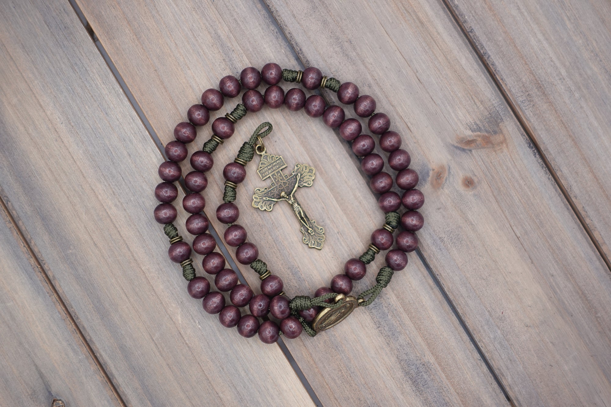 Handcrafted rosary featuring burgundy wood beads with bronze crucifix and Miraculous Medal centerpiece