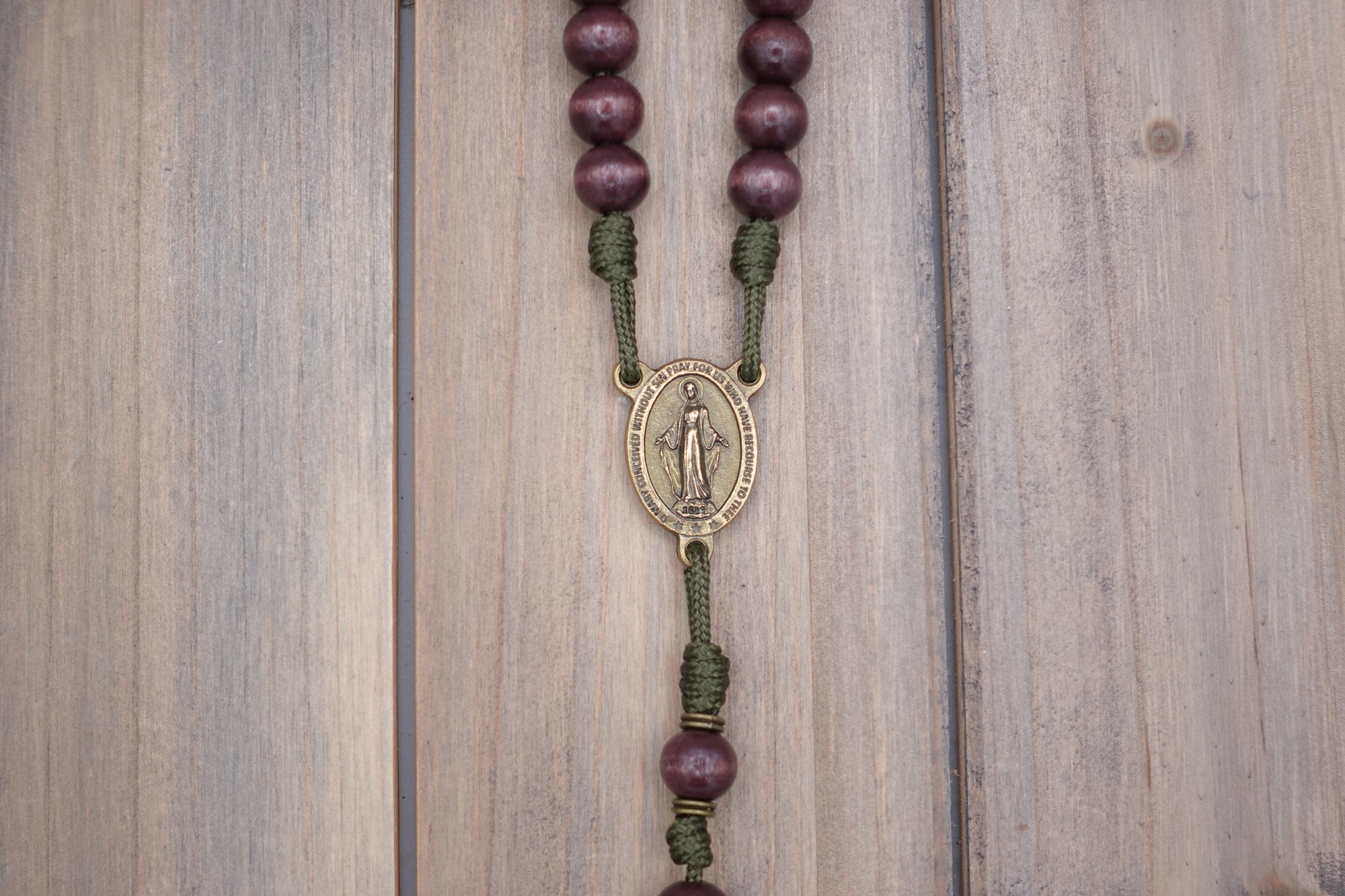 Close-up of bronze Miraculous Medal and paracord craftsmanship on handmade Mount of Olives rosary