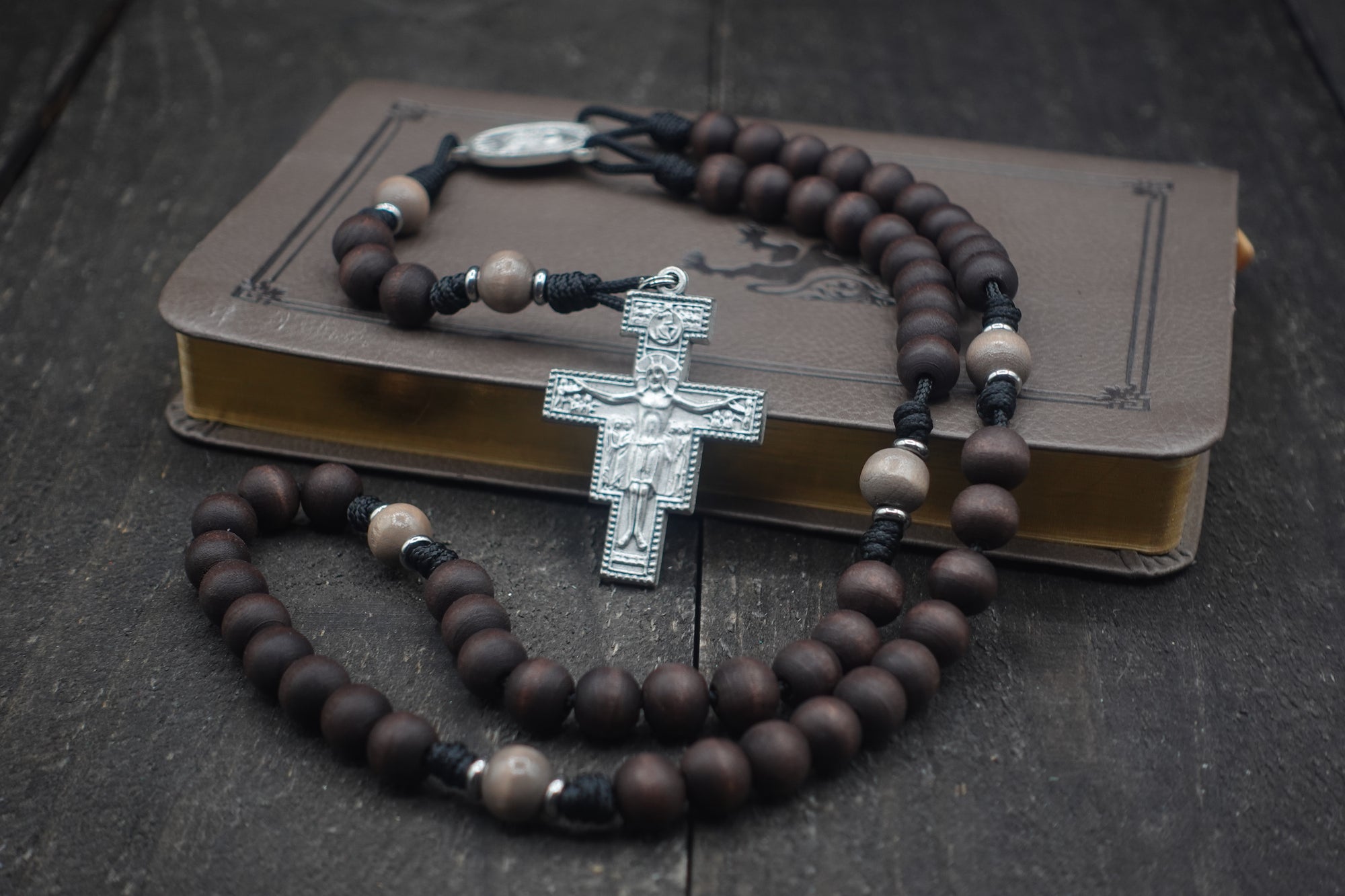 Padre Pio rosary with walnut and light gray wooden beads, silver San Damiano crucifix, and black paracord