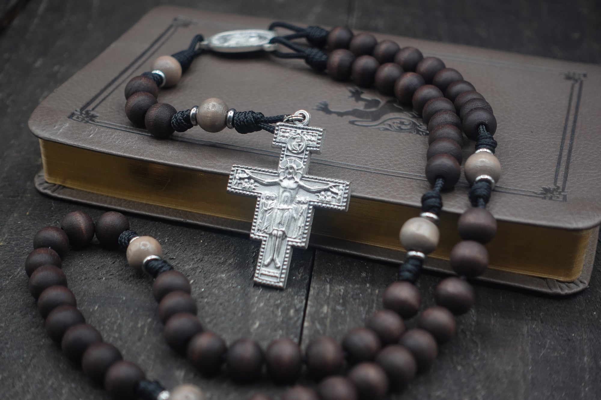 Padre Pio rosary with walnut and light gray wooden beads, silver San Damiano crucifix, and black paracord