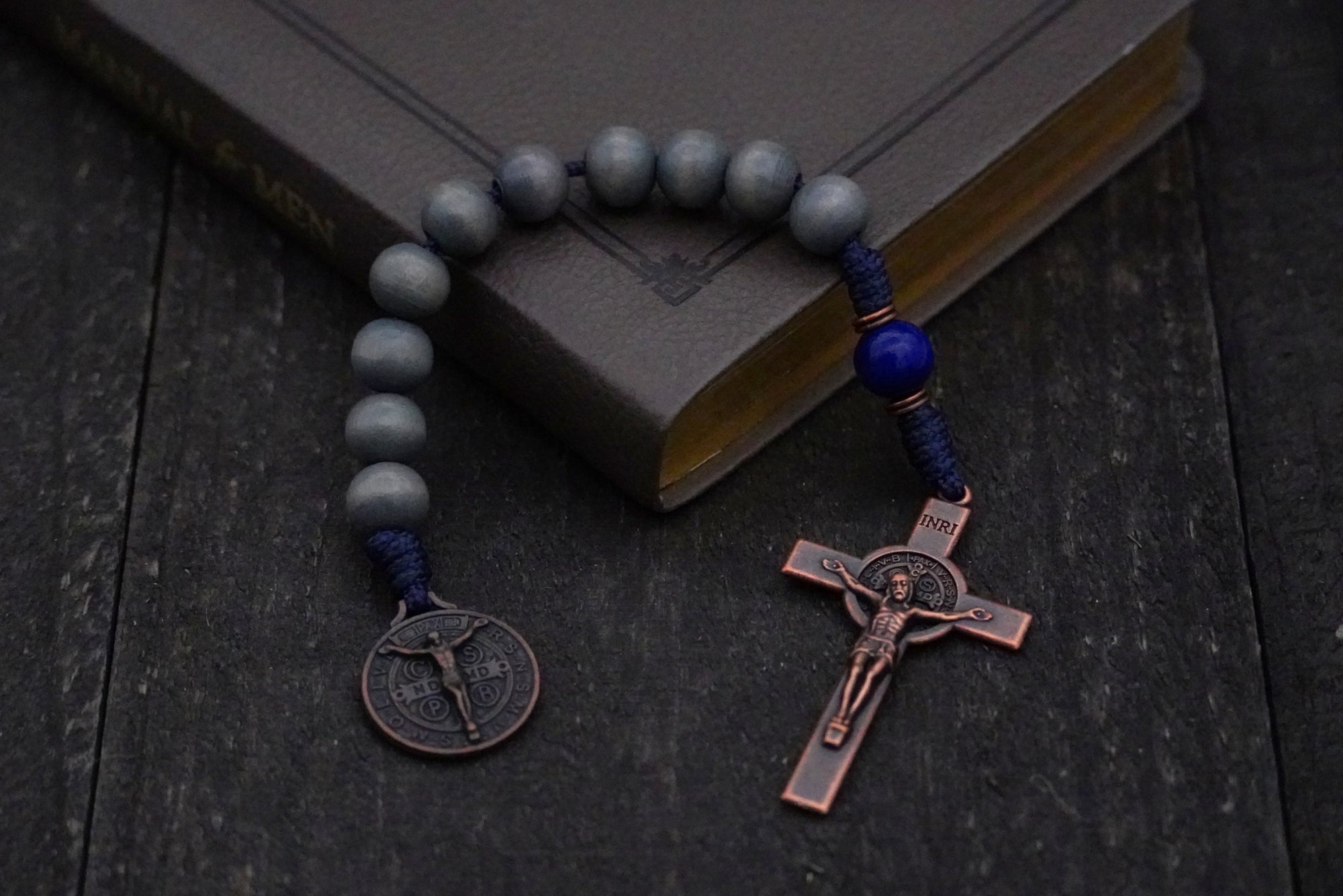 Pocket Sword of the Spirit rosary with lunar and royal blue wood beads, copper St. Benedict crucifix, and navy paracord