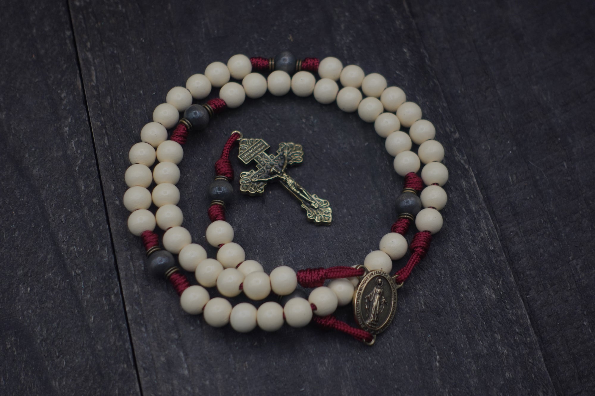 pope Leo XIV rosary by Runewood Rosary combining white and charcoal wood beads, bronze crucifix, and burgundy paracord for faithful devotion