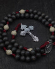 Close-up of silver Pardon crucifix on Pope Leo XIV rosary with charcoal and white wood beads
