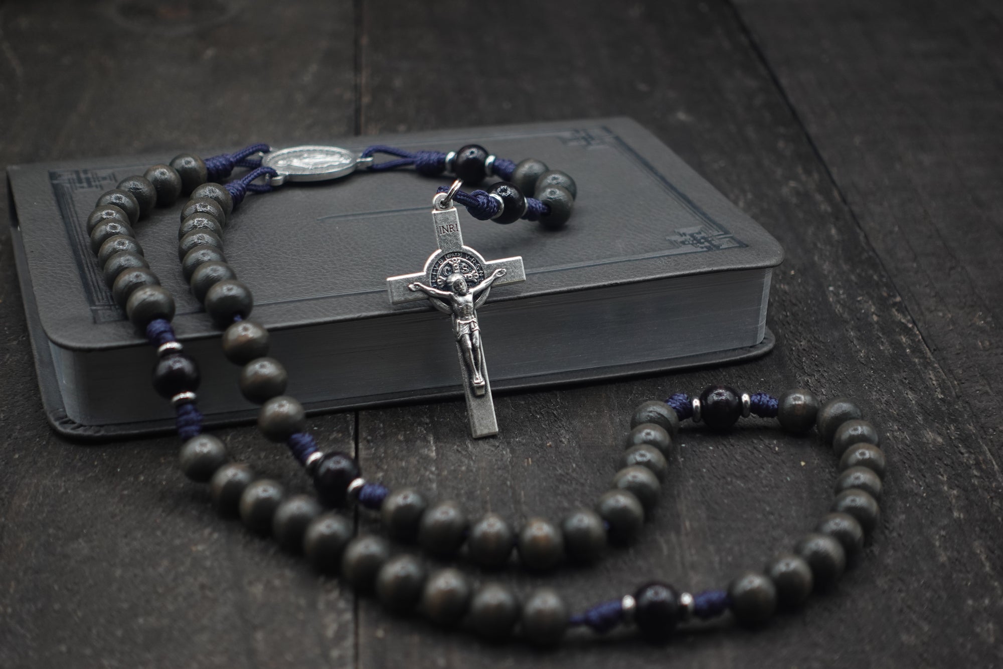 Sanctus rosary with charcoal and black wooden beads, silver St. Benedict crucifix, and navy paracord