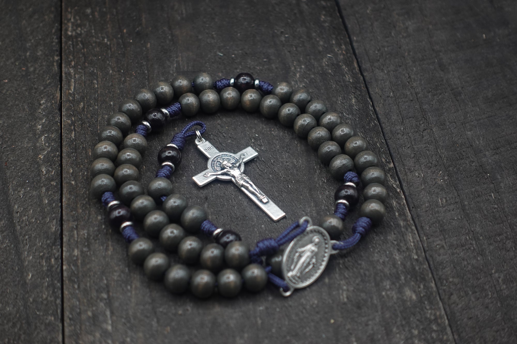 Close-up of silver St. Benedict crucifix on Sanctus rosary with charcoal and black wooden beads