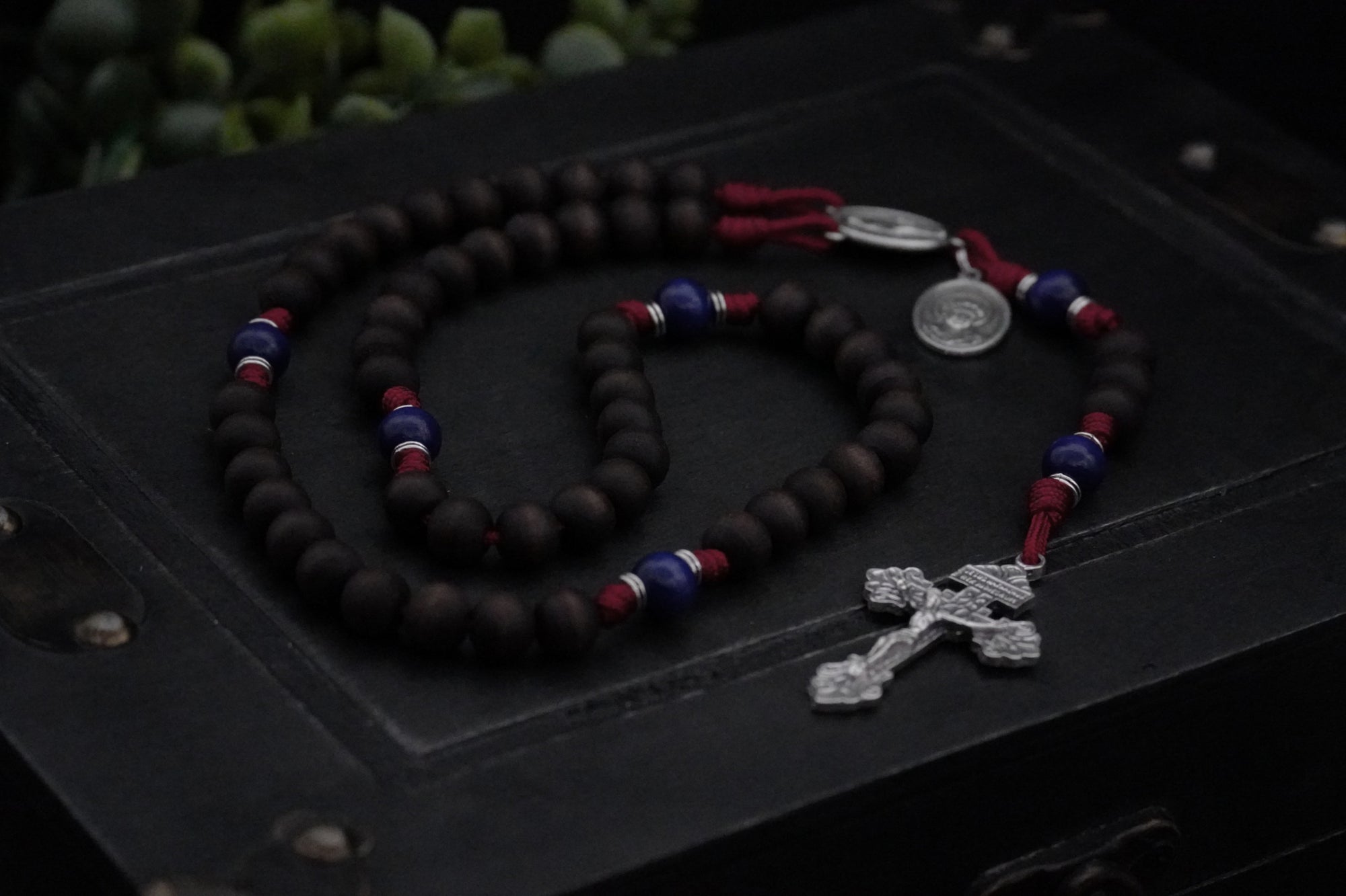 St. Carlo Acutis rosary with walnut and royal blue wooden beads, silver Pardon crucifix, and durable burgundy paracord