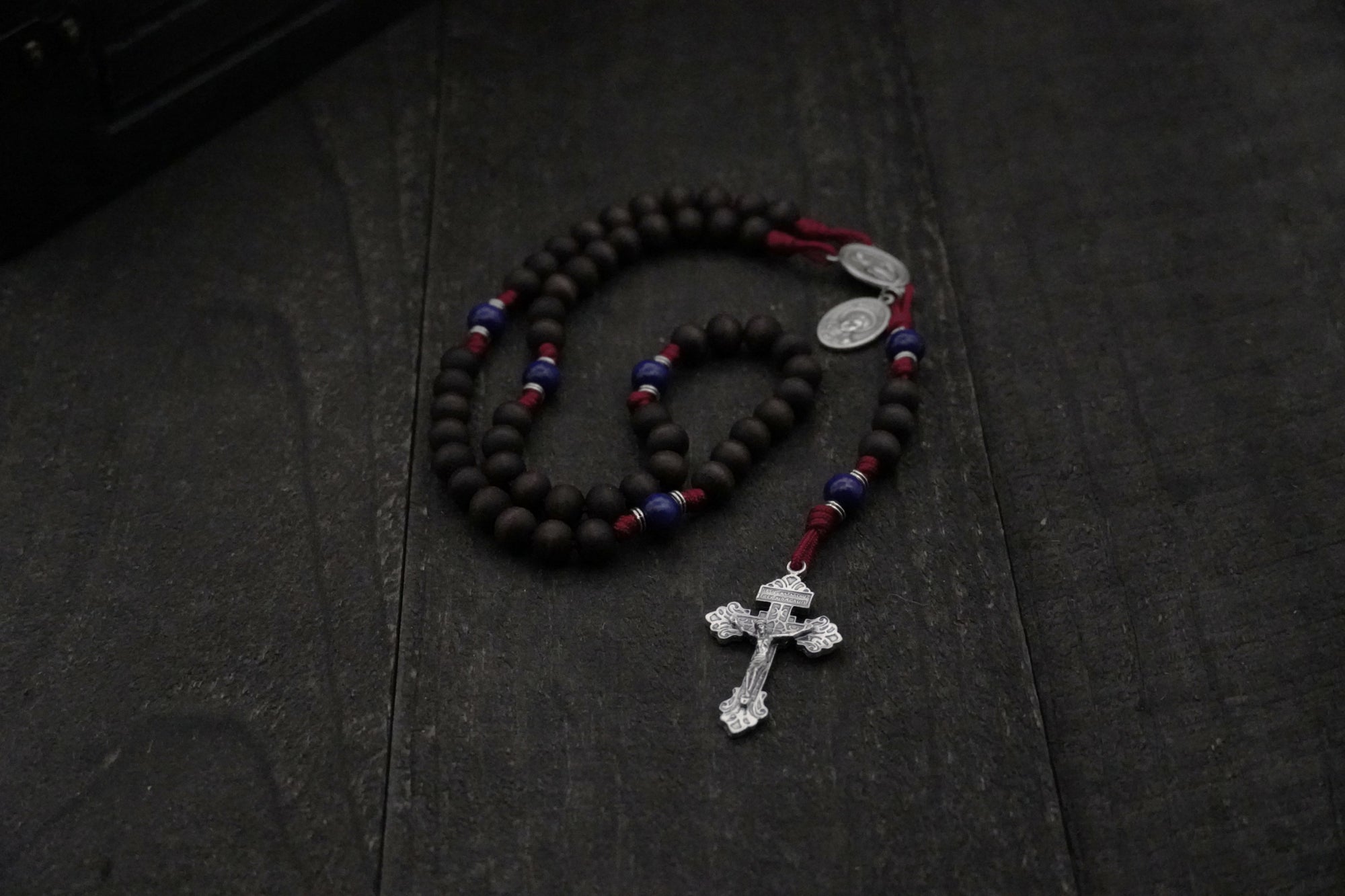 St. Carlo Acutis rosary by Runewood Rosary combining walnut wood beads, silver crucifix, and burgundy paracord for faithful devotion